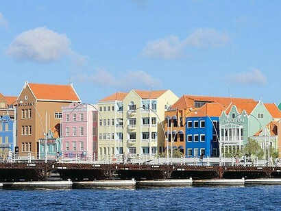 This vibrant waterfront scene captures the "sherbet colors of the Caribbean" that adorn the historic buildings of Willemstad, a UNESCO World Heritage City