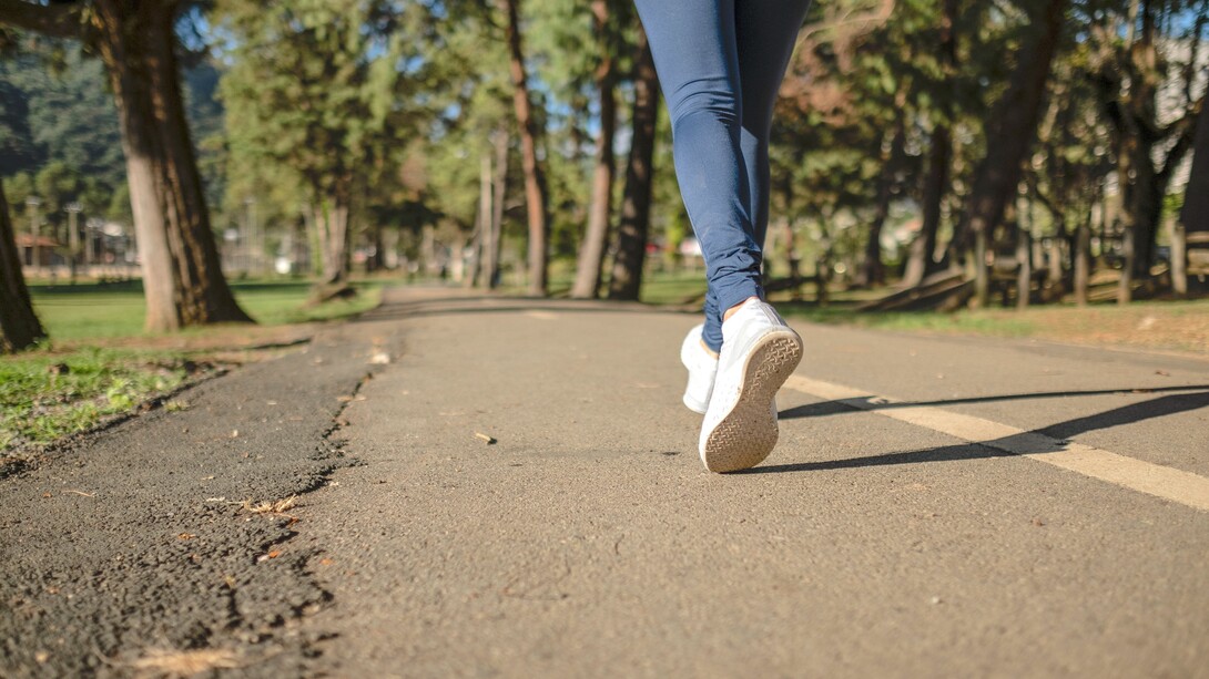 Pessoa de jeans azul e tênis branco andando na estrada