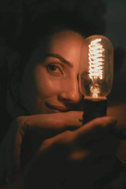 Uma mulher encara a luz no meio da escuridão, enquanto sombras atravessam o enquadramento. Como na letra de “Joshua”, a claridade aqui deixa de esconder aquilo que precisa ser enfrentado