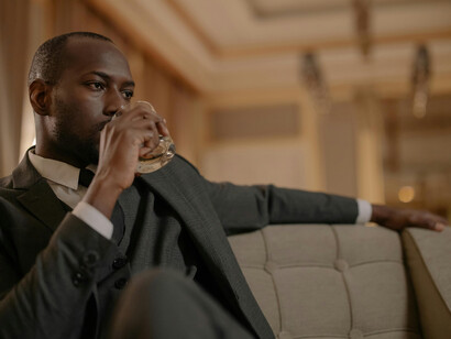 A man drinking whiskey, sitting alone in his living room