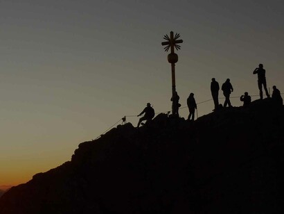 Mountaineers climbing in the spirit of togetherness as the world around them is in the midst of sunset