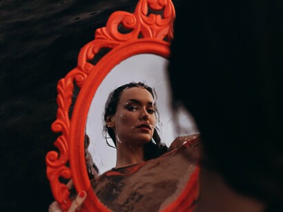 Mulher se observa no espelho. A adaptação não significa abandonar quem você é, mas sim uma maneira de ampliar seus horizontes e de integrar novas perspectivas à sua história pessoal. É possível adotar novos hábitos e valores culturais sem renunciar às suas raízes