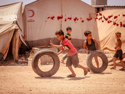 Children find joy in play despite the harsh realities around them, embodying resilience in a refugee camp in Syria amidst ongoing global conflicts