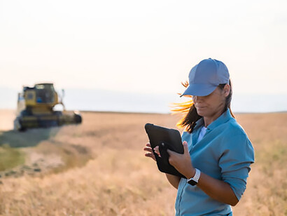Embracing smart agriculture, a female farmer surveys her field with a digital tablet in hand