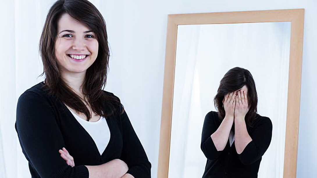 Woman smiling while reflection has hands over face