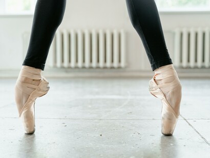 A person standing on their toes wearing ballet shoes 