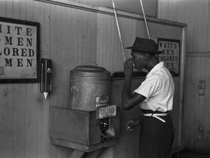Colored drinking fountain from mid-20th century with african-american drinking