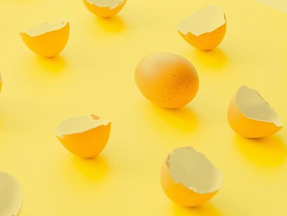 A whole egg next to cracked eggs