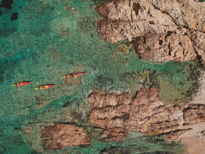The breathtaking sea view from above Isola Rossa, Sardinia, Italy, reveals vibrant shades of blue that blend seamlessly with the horizon along the northwest coast