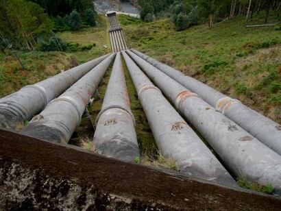 In Geesthacht, Germany, a large pipe rests beside a forest, symbolizing the connection between summer energy, electricity, and nature’s greenery