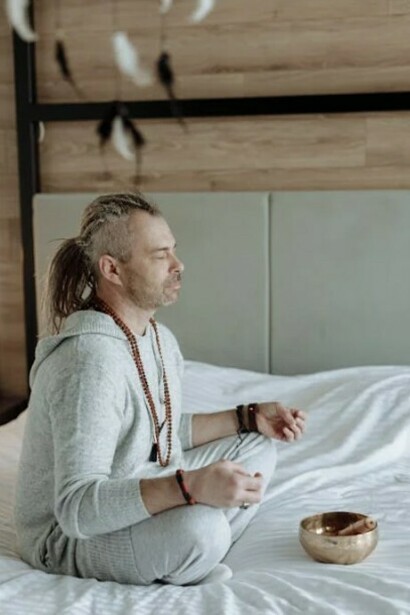 A man meditating peacefully while sitting on his bed
