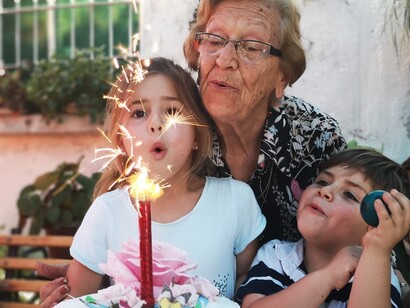 Nonna con i suoi due nipotini davanti a una scintillante candela di compleanno