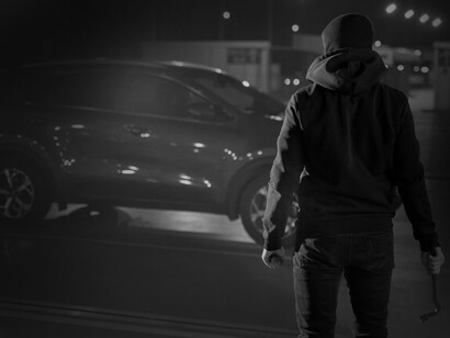 Sous la lumière tamisée, l'individu encapuchonné prépare son prochain coup dans le sombre jeu du vol