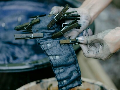 Tingimento artesanal de tecido. Bordados, rendas, cerâmica aplicada e tingimentos naturais são integrados nas peças como forma de destacar o saber-fazer local