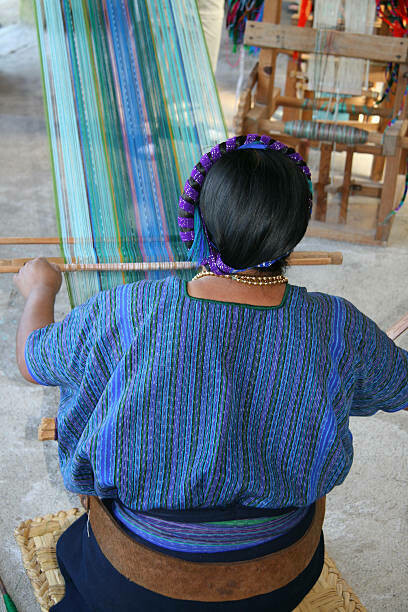 A Mayan woman weaving traditional textiles by Lake Atitlán in Guatemala, showcasing Mayan weaving techniques