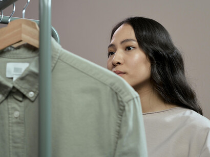 A woman looking at sweaters as a symbol of sustainable fashion and eco-friendly clothing