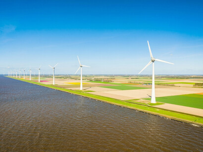 Wind turbines generating clean electricity along the shoreline of a wind farm.