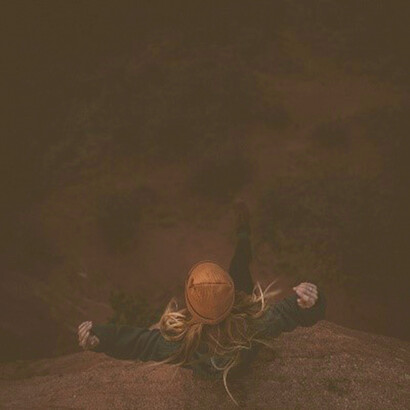 Embodying feminine consciousness, a woman sits serenely on the rocks amidst the hills, connecting with nature and her inner wisdom