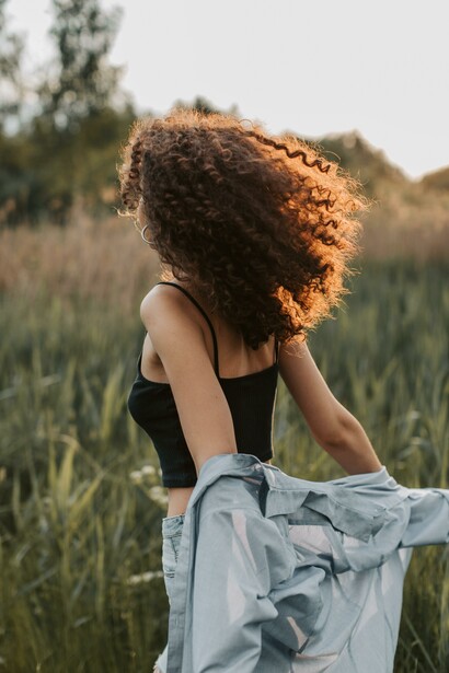 A woman looking out into a field holding her jacket