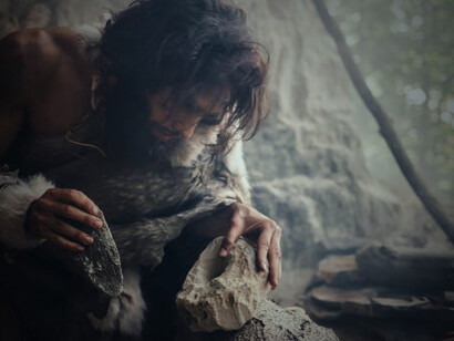 A Neanderthal, clad in animal skins, grips a sharp stone attached to a hidden handle—the earliest form of a hand axe, symbolizing one of humanity’s first great steps in toolmaking
