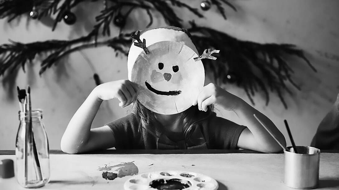 "A little girl wears a reindeer mask, her face beaming with a joyful smile