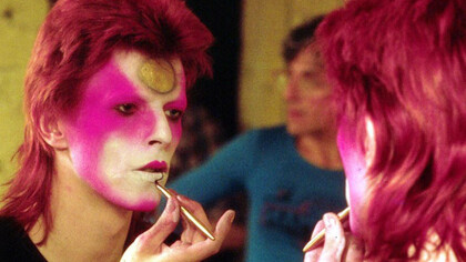 David Bowie no camarim maquiando-se como Ziggy