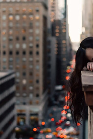 A young woman leans on a rooftop railing in New York City, overwhelmed and exhausted — a quiet moment of burnout in the pursuit of unpaid opportunity