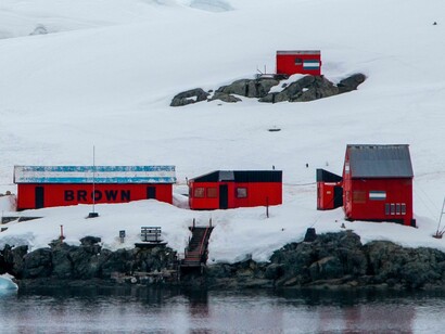 Estación de investigación roja ubicada en el paisaje helado de la Antártida junto al mar, que muestra la exploración remota