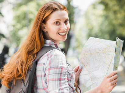 A young woman holding a map in a park, navigating her new beginnings in a foreign country as part of love migration and cultural adaptation