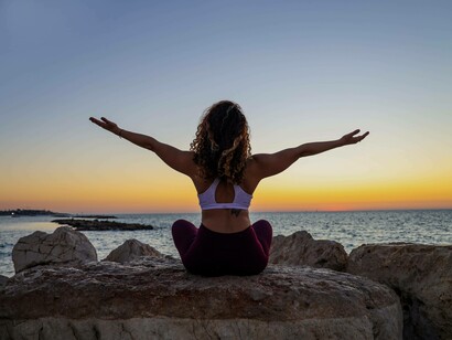 A woman sitting on a rock at sunset offering her gratitude for the hard work she put in to battle her ADHD