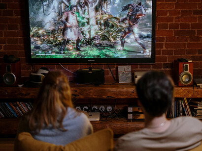 A couple laughing and bonding while playing a console game, enjoying their shared hobby of gaming together