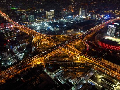 A maze of illuminated roads going through a bustling cityscape, reflecting the intricate systems shaping modern economic power