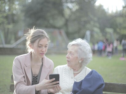 An elderly woman is alongside her younger relative and is confused as to how to use this new piece of technology 
