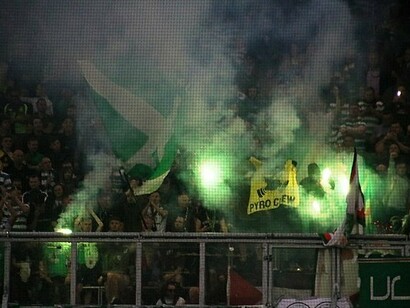 Celtic Park, Glasgow, Scozia. Alcuni tifosi del Celtic incitano la loro squadra sventolando bandiere e accendendo fumogeni verdi