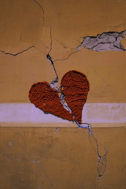 Graffito di un cuore spezzato da una crepa nel muro