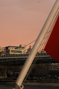 A red and white Turkish flag waves proudly above a bridge and buildings, symbolizing the heart of Türkiye