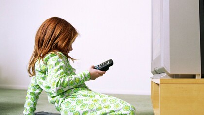 Una niña con el mando a distancia de la televisión