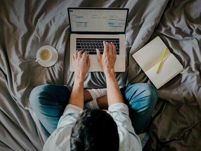 A man working on his laptop while still in bed at home
