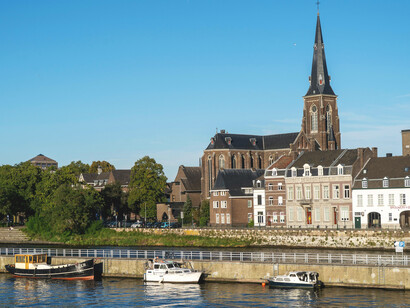 Maastricht, the Netherlands, historic riverside architecture and church towers reflecting the timeless charm of Maastricht under a clear summer sky