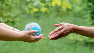 Two individuals embracing the world globe as a symbol of global unity and responsibility