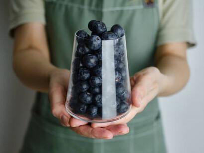 Organic delicious blueberries in a glass in the hands of a girl