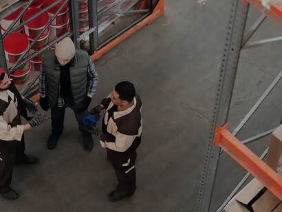 Men labor within a sprawling warehouse, maneuvering a pallet truck with precision and purpose