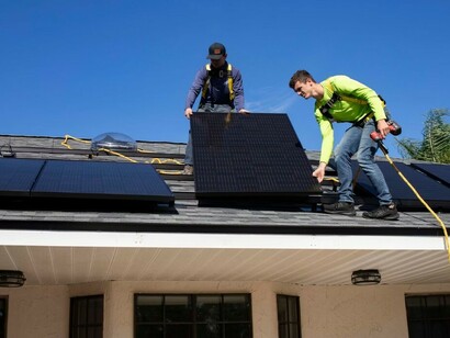 A man installs solar panels atop a building, turning sunlight into energy