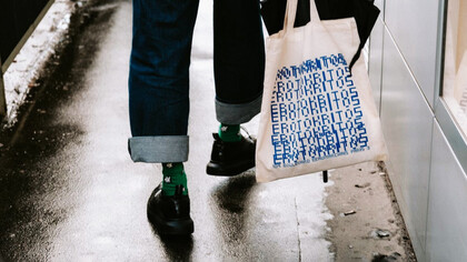 Una chica sostiene su 'tote bag' blanca. 'Tote' viene del verbo 'to tote', que significa «llevar»