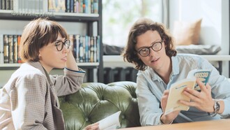 Mulher lê um livro e debate com seu colega