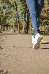 Pessoa de jeans azul e tênis branco andando na estrada