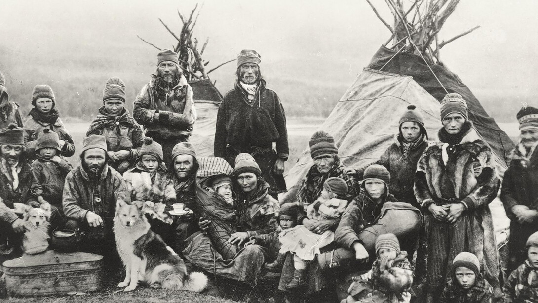 Nordic Sámi people in Sápmi (Lapland) gathered in front of two traditional Lavvu tents, showcasing their nomadic lifestyle that has endured for centuries across the vast northern landscapes of Norway and Sweden