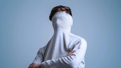 Hombre esconde el rostro en el cuello de su jersey. Identidad es el concepto que cada persona tiene de su individualidad y de su pertenencia a grupos