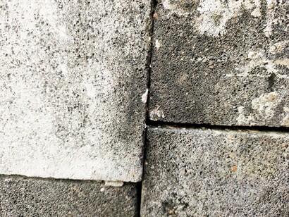 Un muro di blocchi di cemento grigi, con una linea verticale e una orizzontale che ne evidenziano la trama porosa