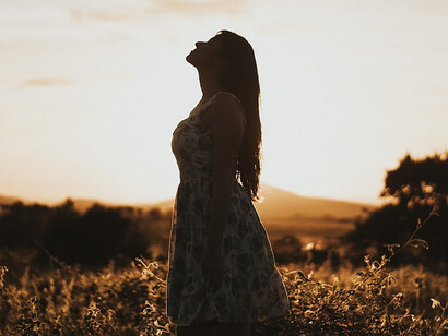 A woman's silhouette stands in a grassy field, embodies the essence of self-discovery and joyful authenticity